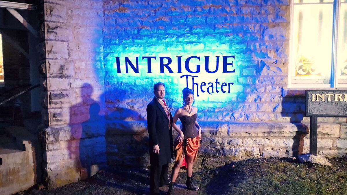 Sean-Paul and Juliana Fay beneath the illuminated Intrigue Theater sign